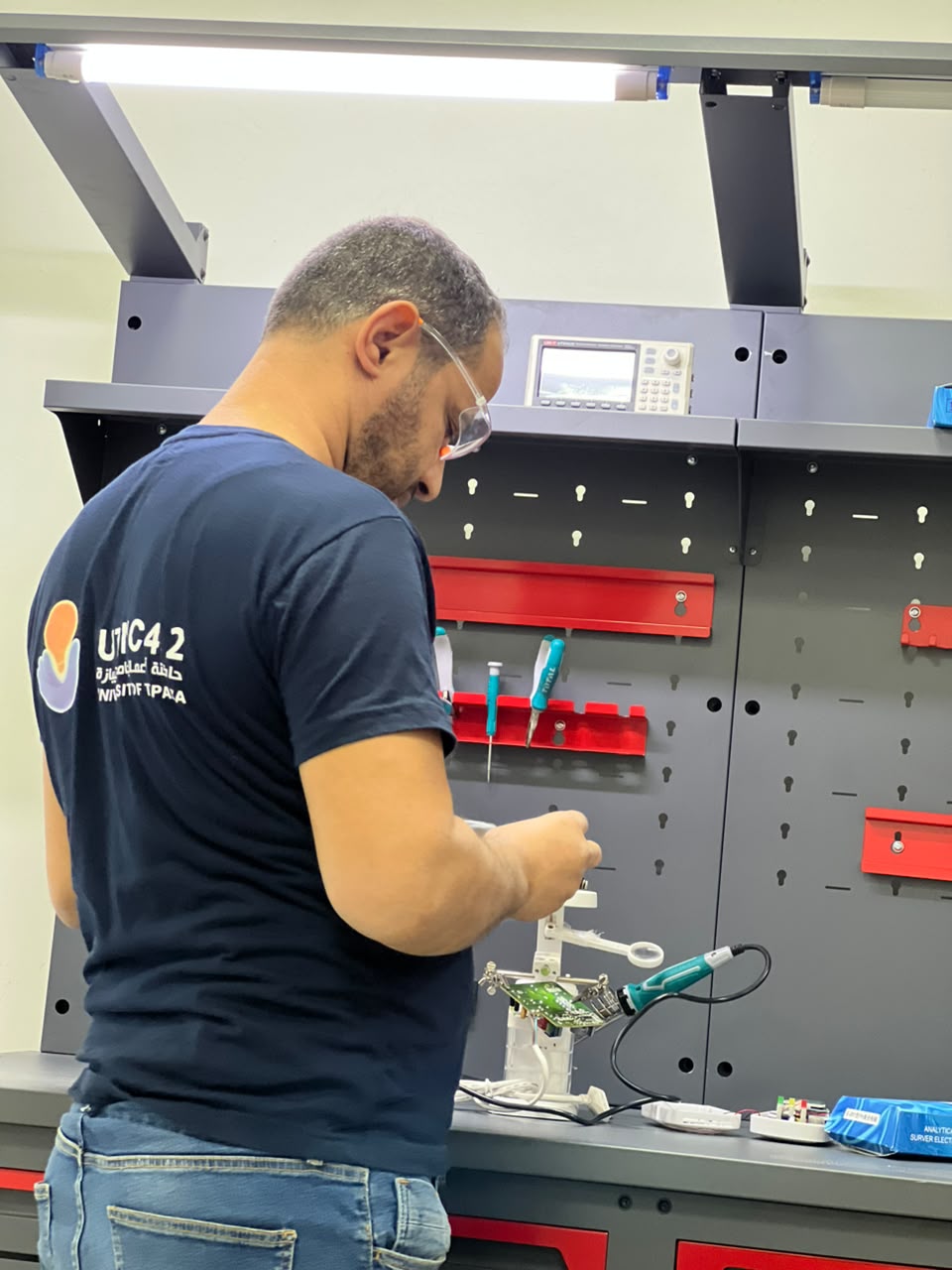 مهندس يركّب نموذجا إلكترونيا أوليا على طاولة النماذج الأولية بالحاضنة